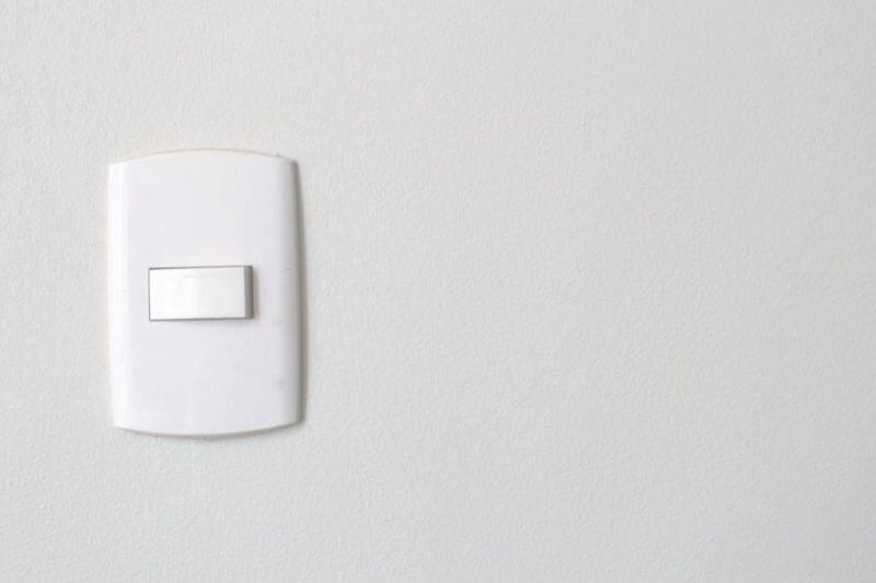 Interruptor simples sobre parede branca.