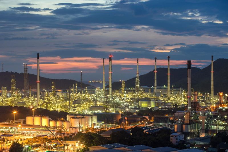 Vista panorâmica de indústria cercada por morros e céu encoberto ao entardecer