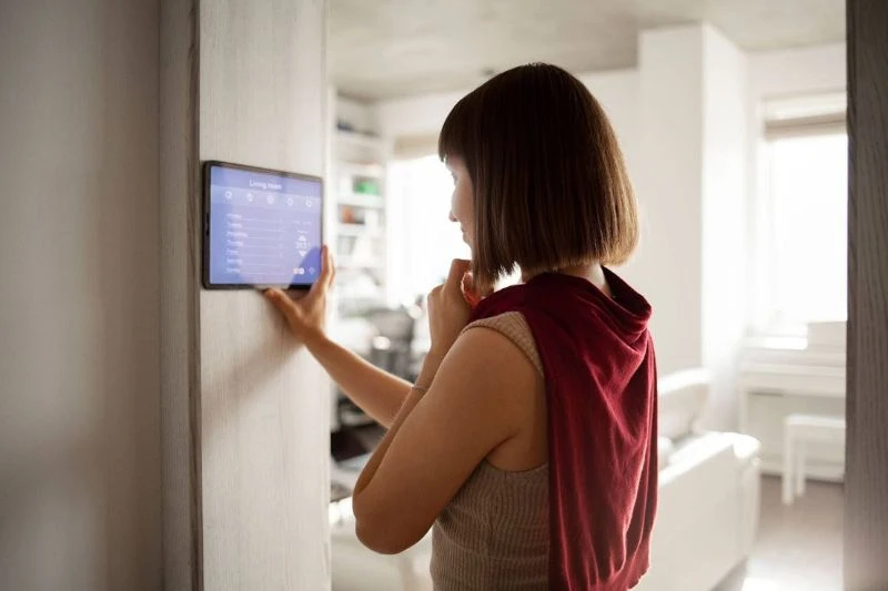 Como contratar uma empresa de automação residencial? Mulher interagindo com um painel de controle em um ambiente residencial.