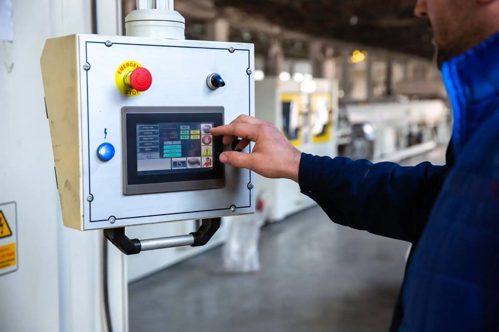 Sensor magnético: o que é, para que serve e como funciona? Operador ajustando configuração de sensor magnético em painel de controle industrial em um ambiente de fábrica