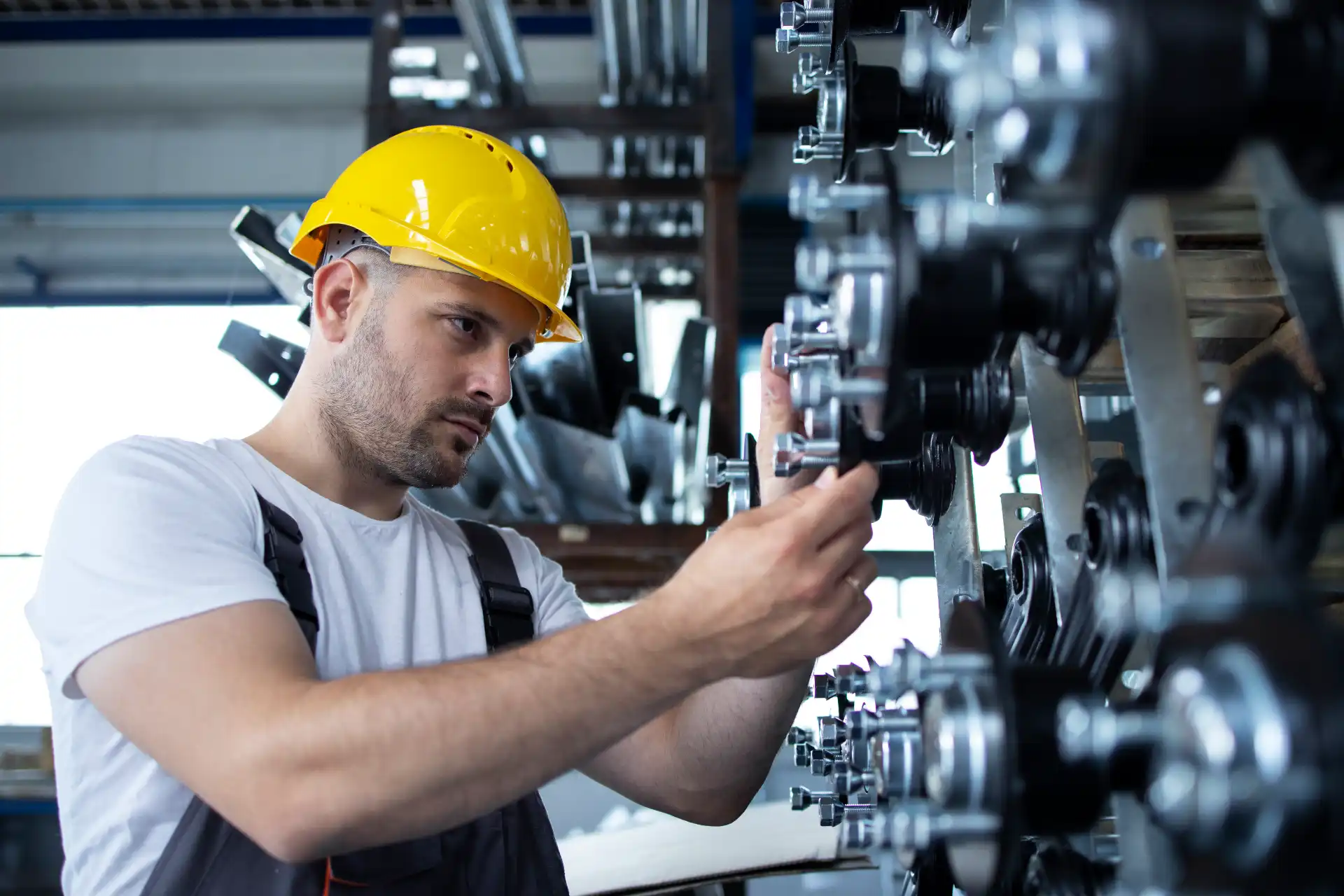Engenheiro ou técnico ajustando peças mecânicas em uma linha de produção industrial, usando capacete de segurança, voltado à manutenção ou montagem.